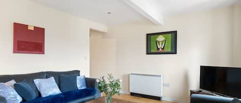 A modern living room with a sofa, a coffee table, a television, and artwork on the walls.