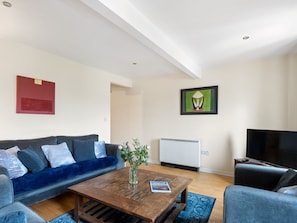 A modern living room with a sofa, a coffee table, a television, and artwork on the walls.