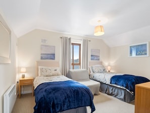 A bedroom with two beds, a window, and a ceiling light.