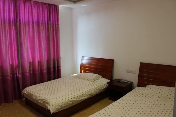 Een slaapkamer met twee bedden, een nachtkastje en een raam met gordijnen.