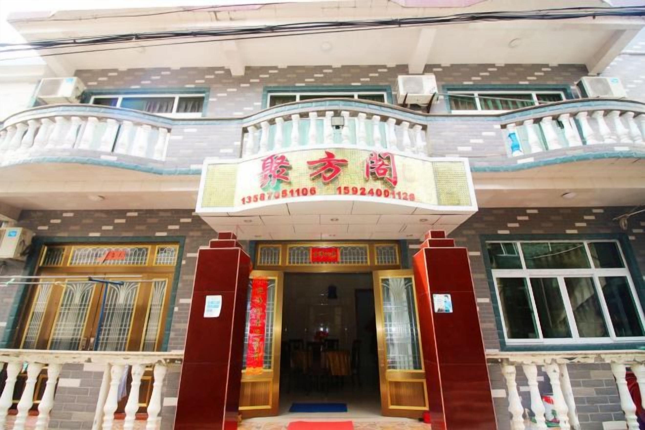 A building with a prominent entrance, a balcony, and a sign with Chinese characters.