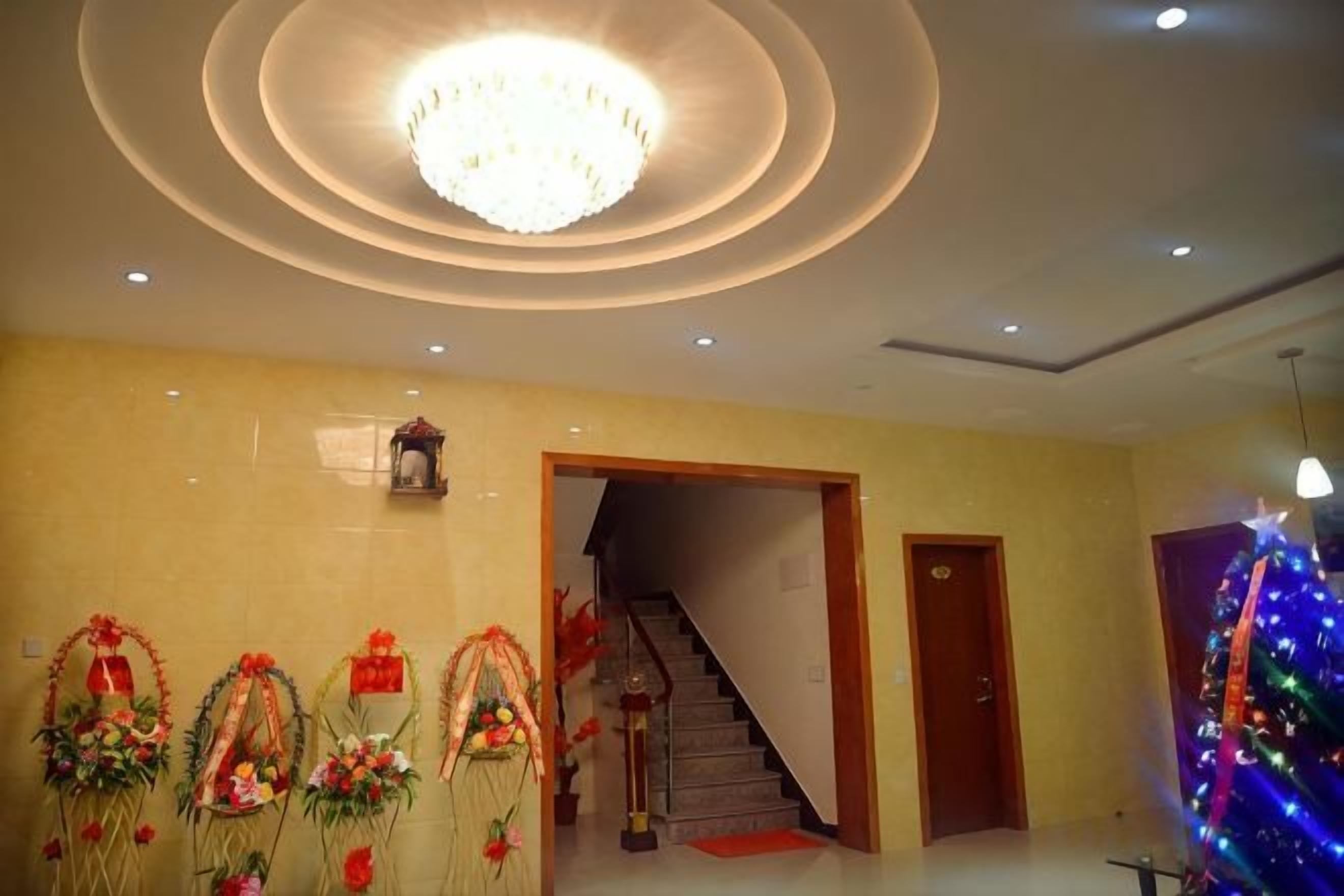 A hotel lobby with a staircase, a chandelier, and floral arrangements.