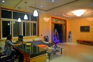A modern living room with a glass coffee table, a sofa, and a person using a laptop. - Jufangge Hotel (Shengsi)
