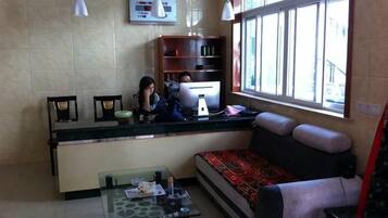 A reception area with a counter, a sofa, a table with items, and a window with a view.