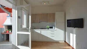 Una cocina moderna con armarios blancos, un microondas y un televisor montado en la pared.