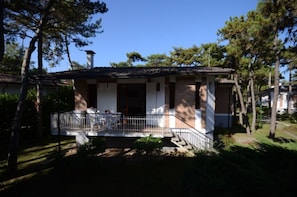 A two-story house with a balcony, surrounded by trees.