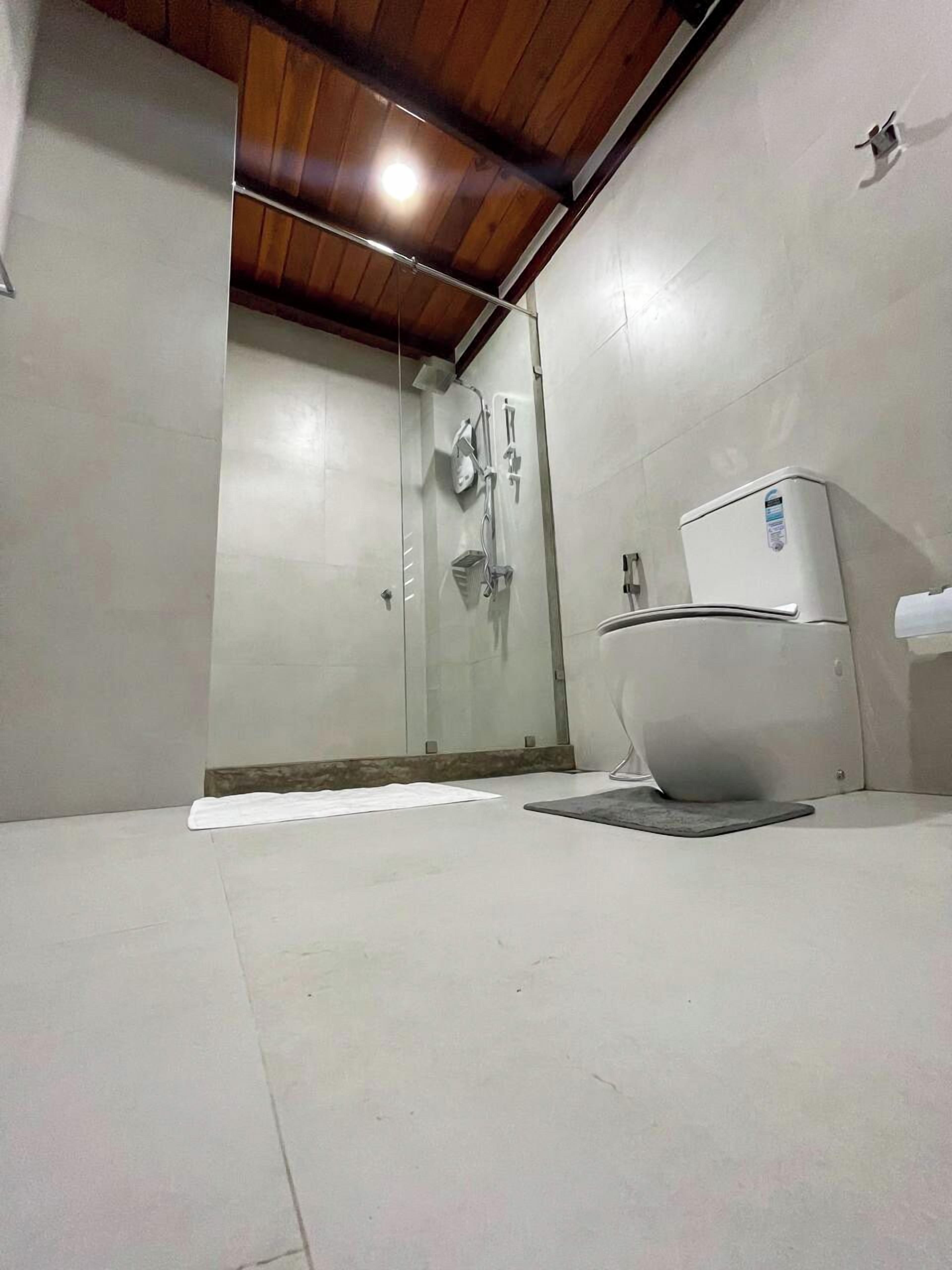 A modern bathroom with a glass shower enclosure, a toilet, and a sink.