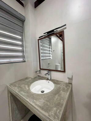 A bathroom with a marble sink, a mirror, and a window with blinds. - Lush Breeze (Kandy)