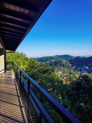 A balcony with a view of a lush green landscape and distant buildings. - Lush Breeze (Kandy)