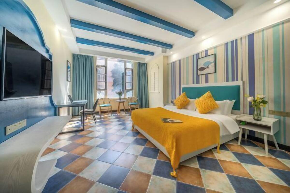 Ein Hotelzimmer mit Bett, Fernseher, Schreibtisch und Stuhl.