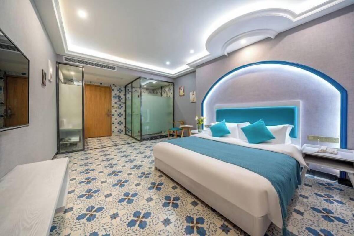 Ein Hotelzimmer mit Bett, Nachttisch und einem Badezimmer mit Dusche.