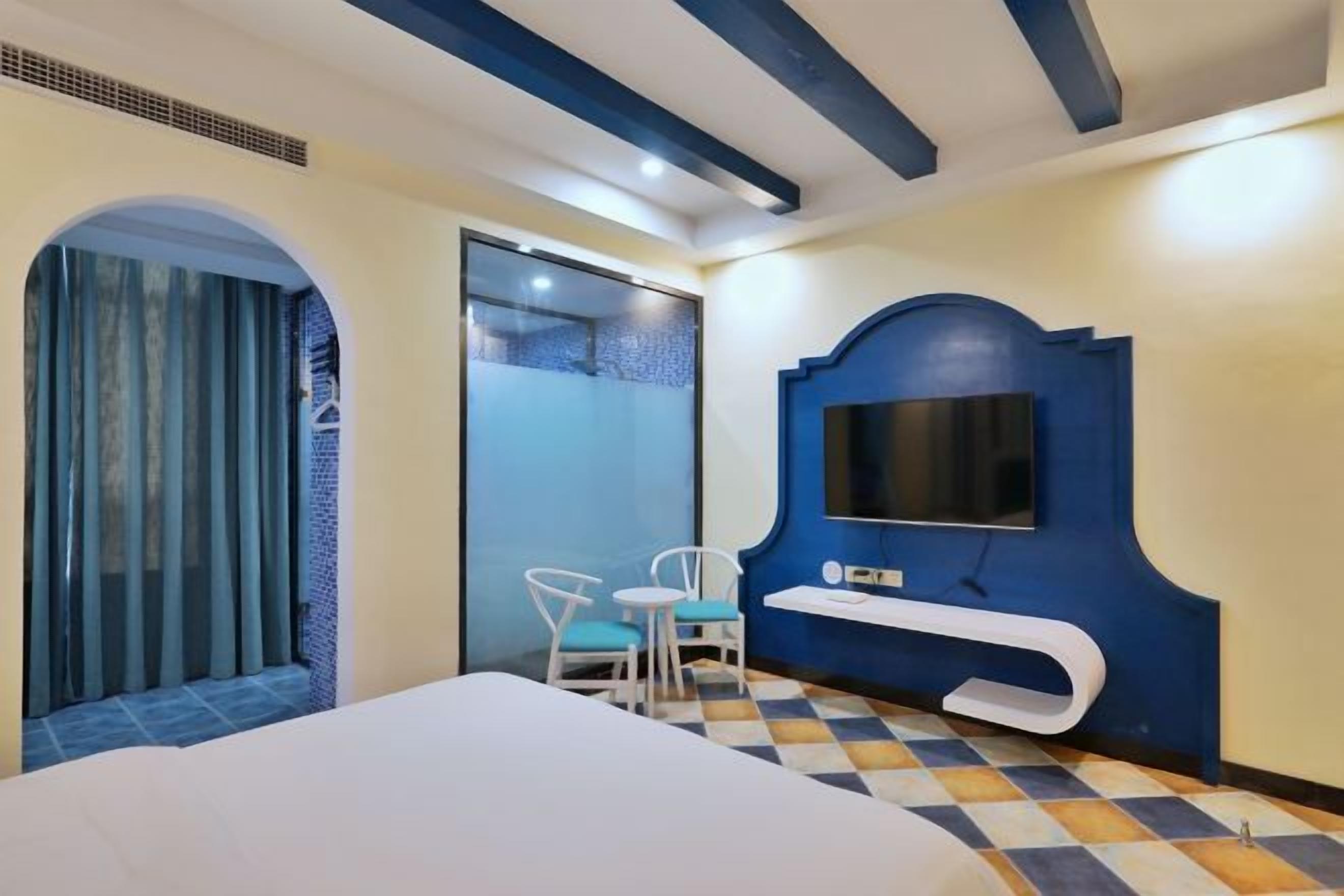 Quarto de hotel com cama, televisão, mesa pequena e cadeira.