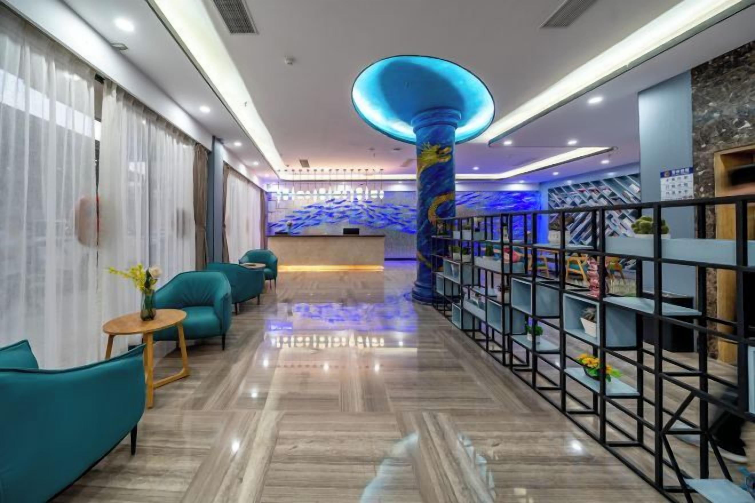 A hotel lobby with a reception desk, teal seating, and a decorative column.