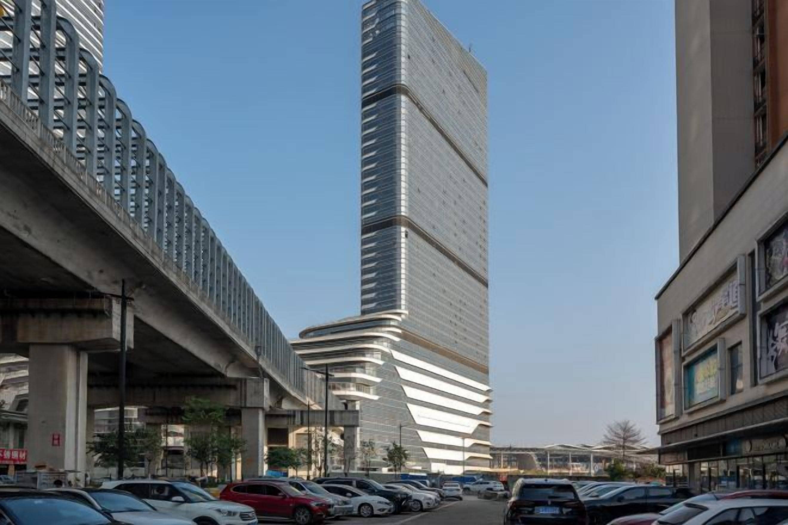 Una calle urbana con edificios altos, un estacionamiento y cielo despejado.