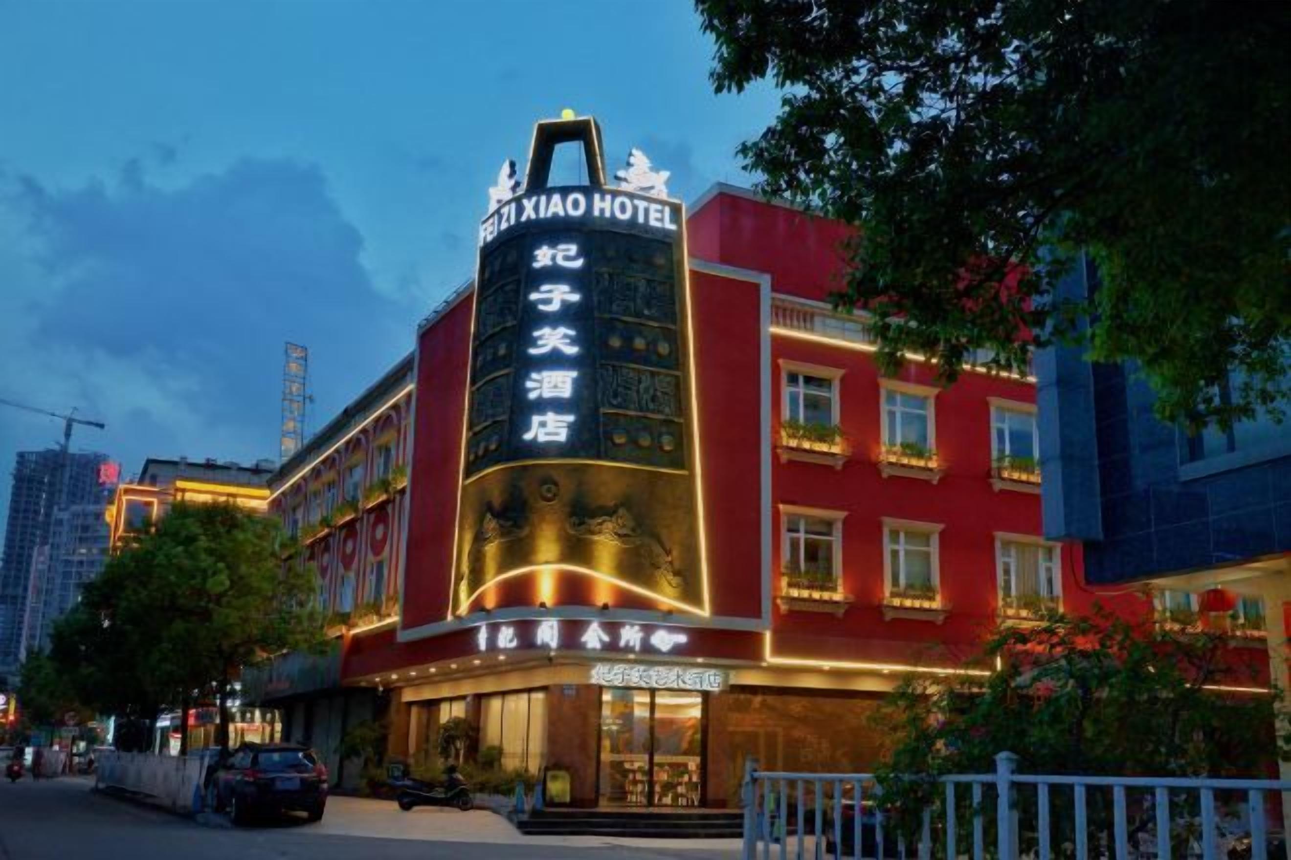 A hotel with a prominent vertical sign, multiple windows, and a well-lit facade.