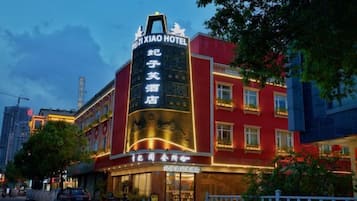 A hotel with a prominent vertical sign, multiple windows, and a well-lit facade.