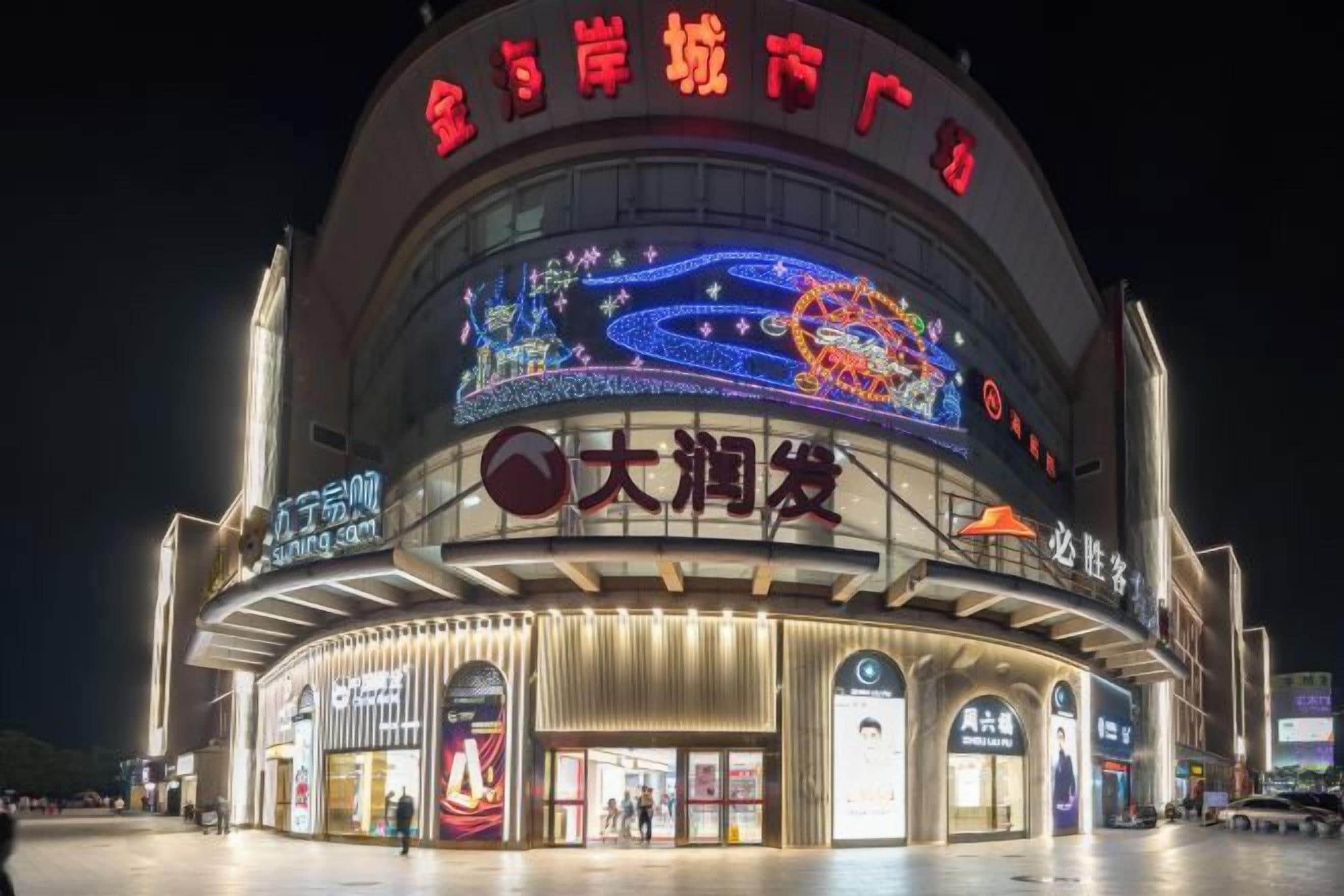 Un grand bâtiment illuminé, doté d’une entrée circulaire et de nombreuses enseignes, dont l’une indique « 大润发 ».