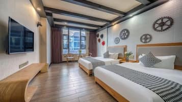 A hotel room with two beds, a TV, a desk, and a window with curtains.