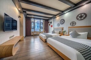 Habitación de hotel con dos camas, televisión, escritorio y ventana con cortinas.