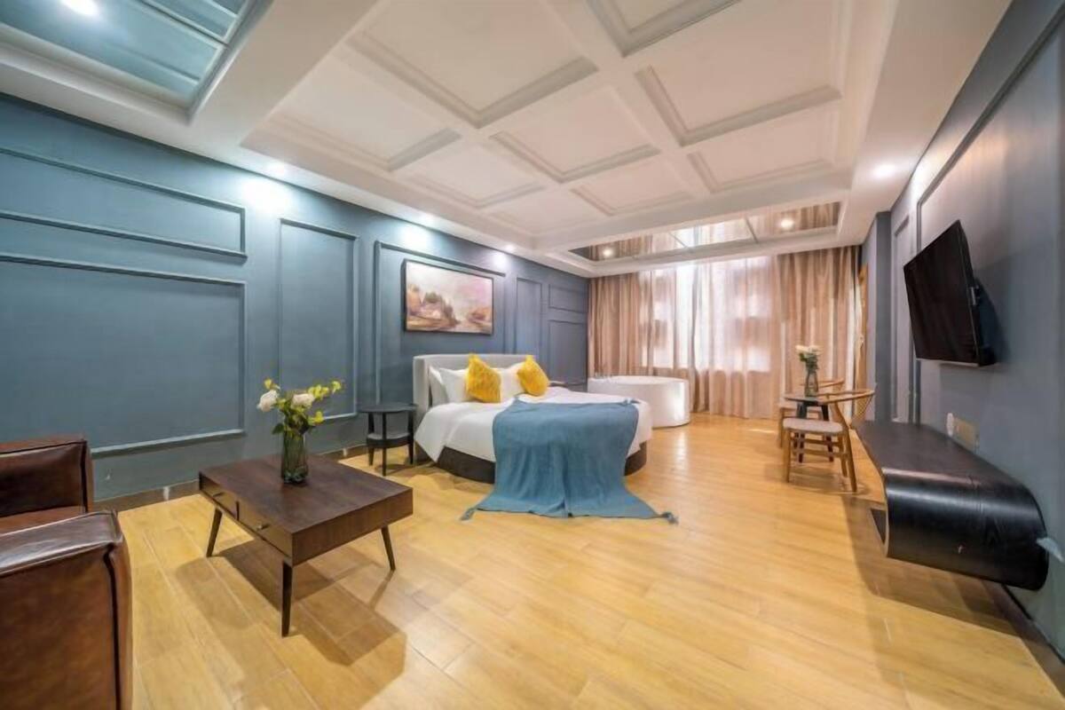 Ein modernes Hotelzimmer mit Bett, einer Couch, einem Couchtisch und einem Fernseher.
