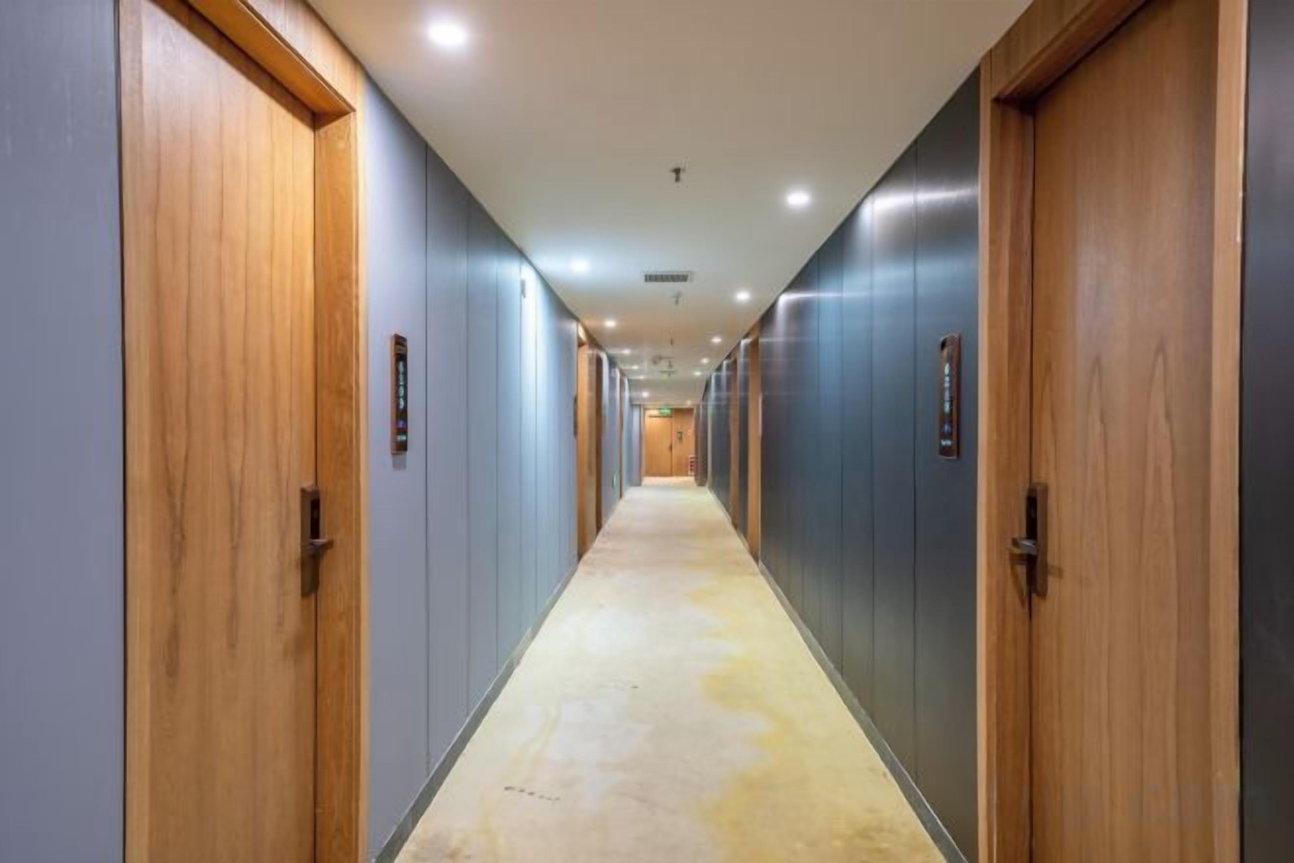 A long, narrow hallway with doors on both sides, leading to individual rooms.