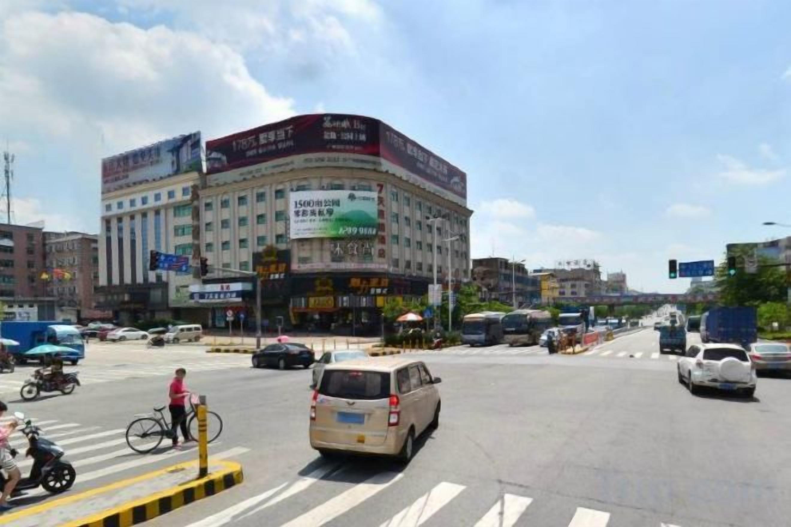 A busy urban intersection with a multi-story building featuring commercial signage.