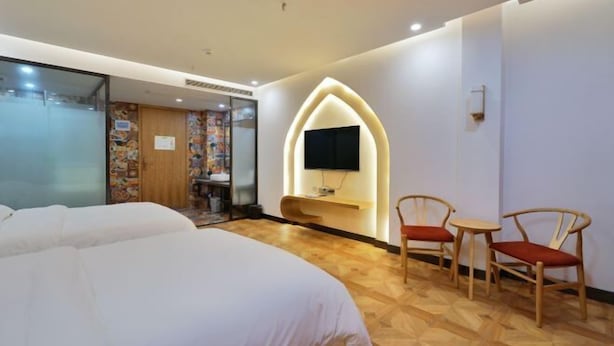 Une chambre d’hôtel avec un lit, un téléviseur fixé au mur, une petite table et deux chaises.