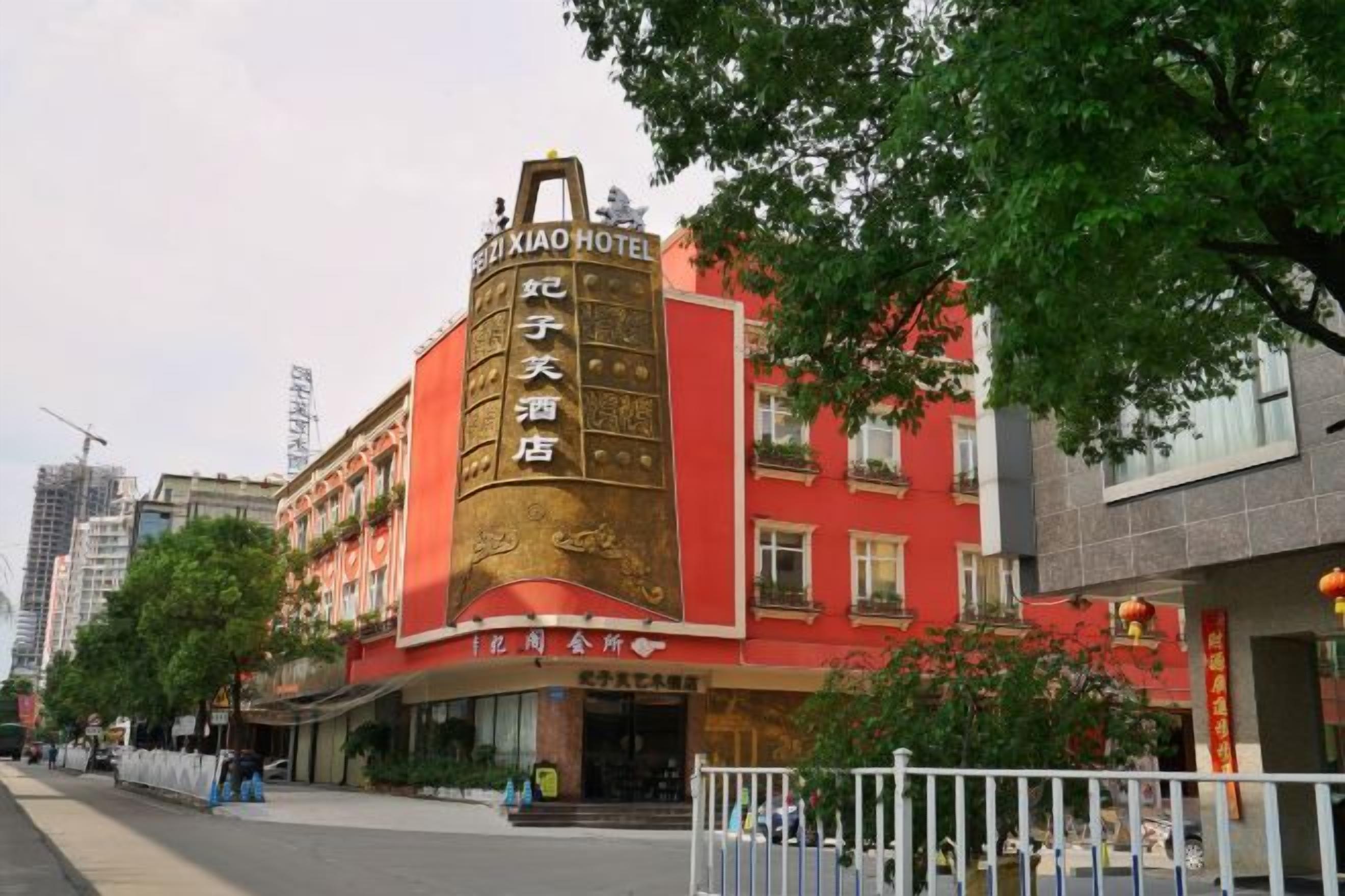 A hotel with a prominent sign, a red facade, and a gated entrance.