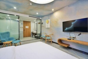 A hotel room with a bed, a TV, a desk, and a chair.
