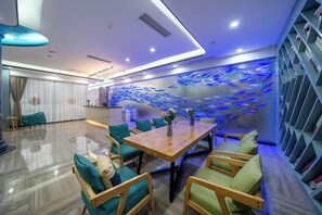 Une chambre d’hôtel moderne dotée d’un coin repas, d’un grand mur décoré d’un aquarium et d’un escalier.