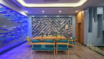 A dining area with a wooden table and teal chairs, a fish wall, and a geometric patterned wall.