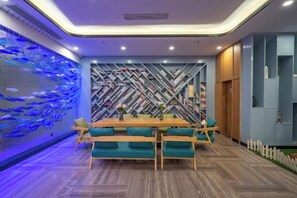Un coin repas avec une table en bois et des chaises de couleur turquoise, un mur décoré de motifs de poissons et un mur orné de motifs géométriques.