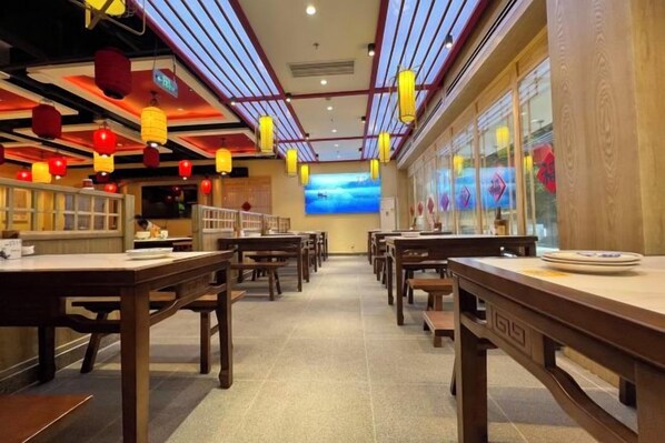 A restaurant interior with tables and chairs, a view of the sky through the windows, and decorative lanterns.