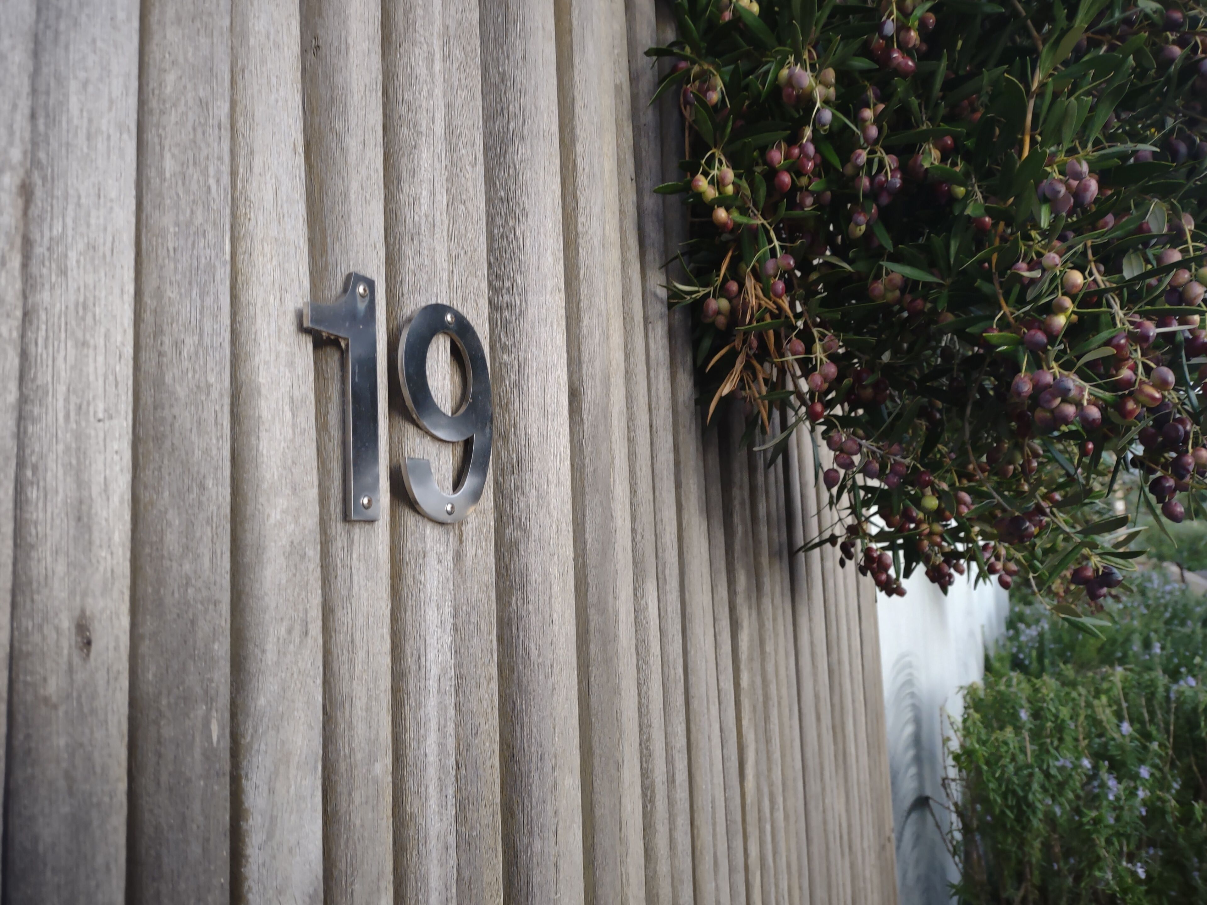 A wooden wall with a metal number '19' sign.