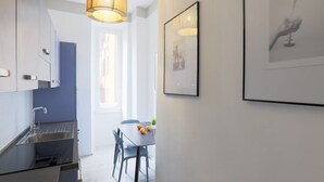 A modern kitchen with a built-in sink, a dining area with a table and chairs, and a large window allowing natural light. - Easylife - Elegant apartment in Ostiense area (Roma)
