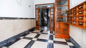 A hallway with a checkered floor, a wooden bookshelf, and a staircase leading to another room. - Easylife - Elegant apartment in Ostiense area (Roma)