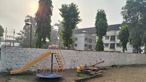 A playground with a slide and climbing structure, surrounded by a paved area and a stone wall. - HOTEL SARIKA (Murbad)