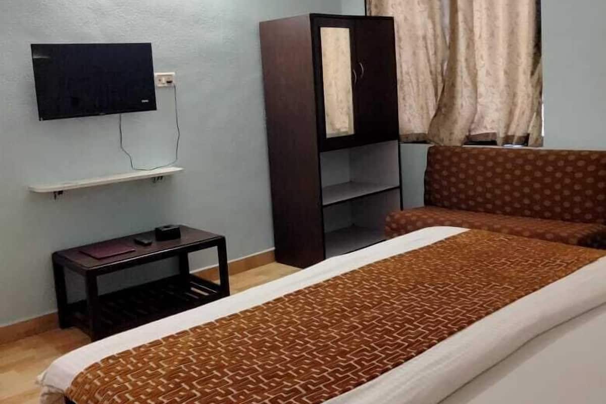 Quarto com uma cama, televisão na parede, ventilador de teto e guarda-roupa.