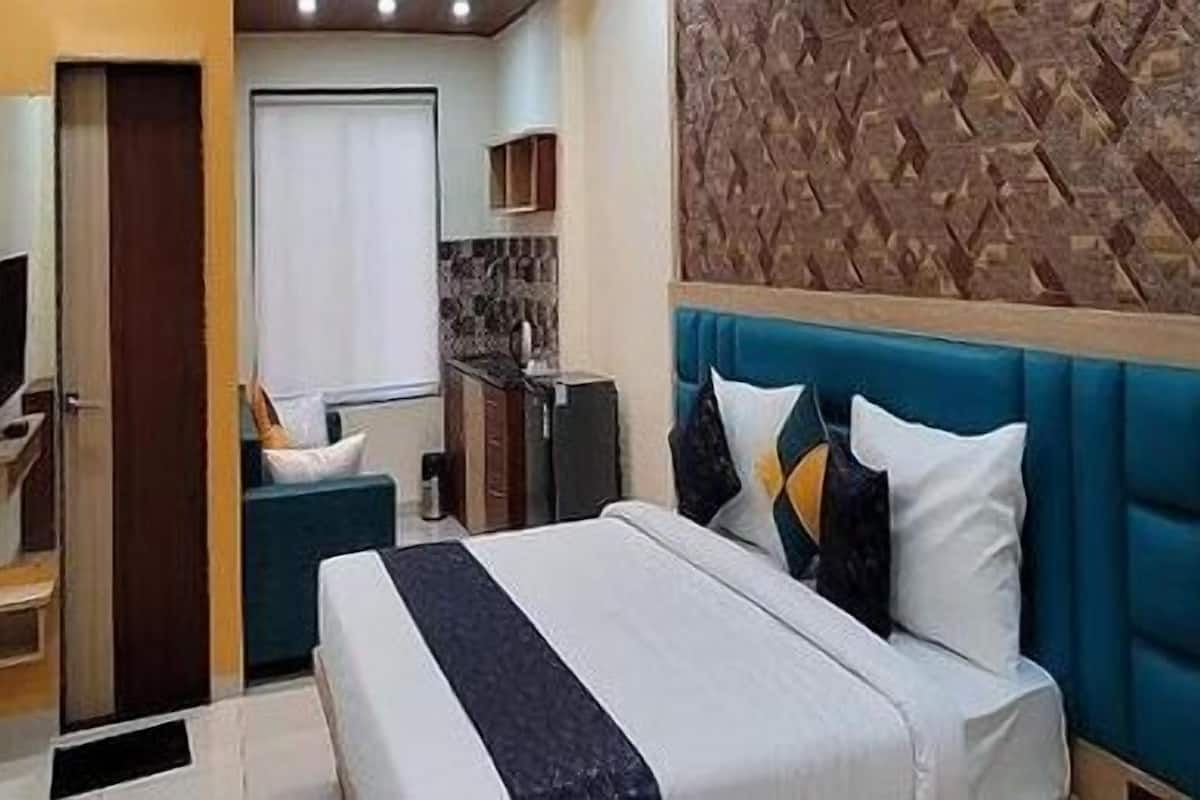 Quarto de hotel com cama, televisão, banheiro e cozinha.