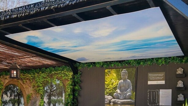 A hot tub with a Buddha statue, a pergola, and a mural of a sky and trees. - Luxurious country house with whirlpool, sauna and private swimming pool (Schoonloo)