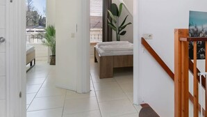 A spacious room with a bed, a large plant, and a painting on the wall. - Luxurious country house with whirlpool, sauna and private swimming pool (Schoonloo)