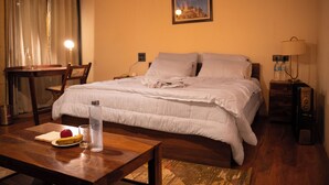 Habitación de hotel ordenada con cama, mesita de noche, lámpara y un cuadro en la pared.