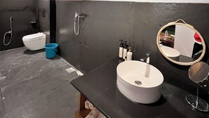 Un baño moderno con techo de madera, un lavabo redondo, un espejo, un inodoro y una ducha.