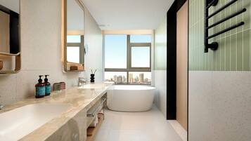 A modern bathroom with a large bathtub, a double sink vanity, and a large mirror.