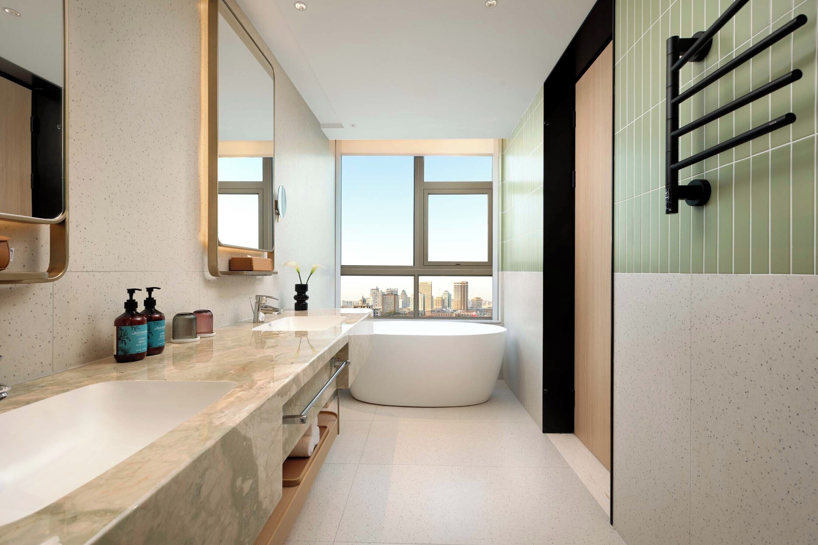 A modern bathroom with a large bathtub, a double sink vanity, and a large mirror.