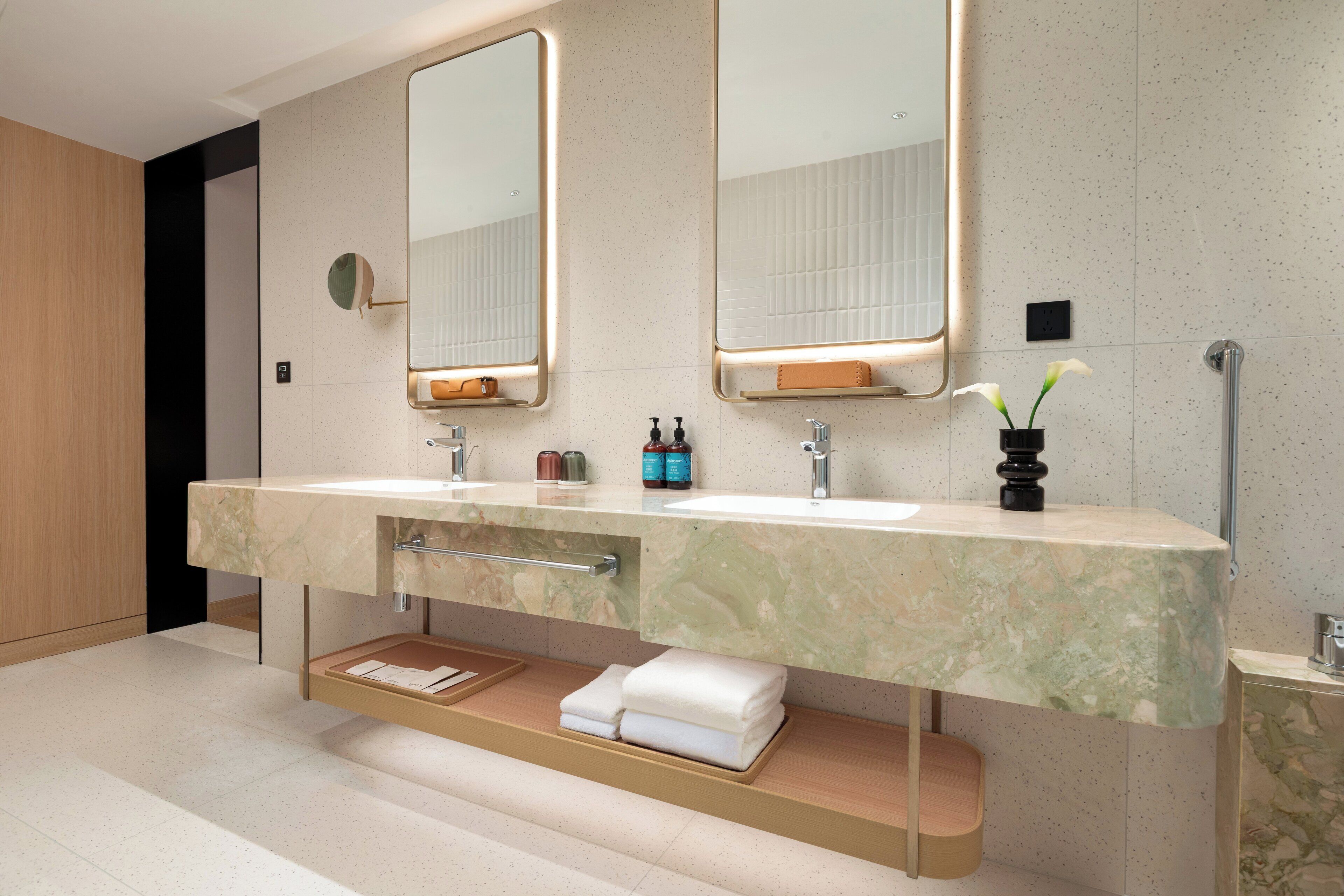 Une salle de bain moderne avec deux lavabos, un grand miroir et un porte-serviettes.