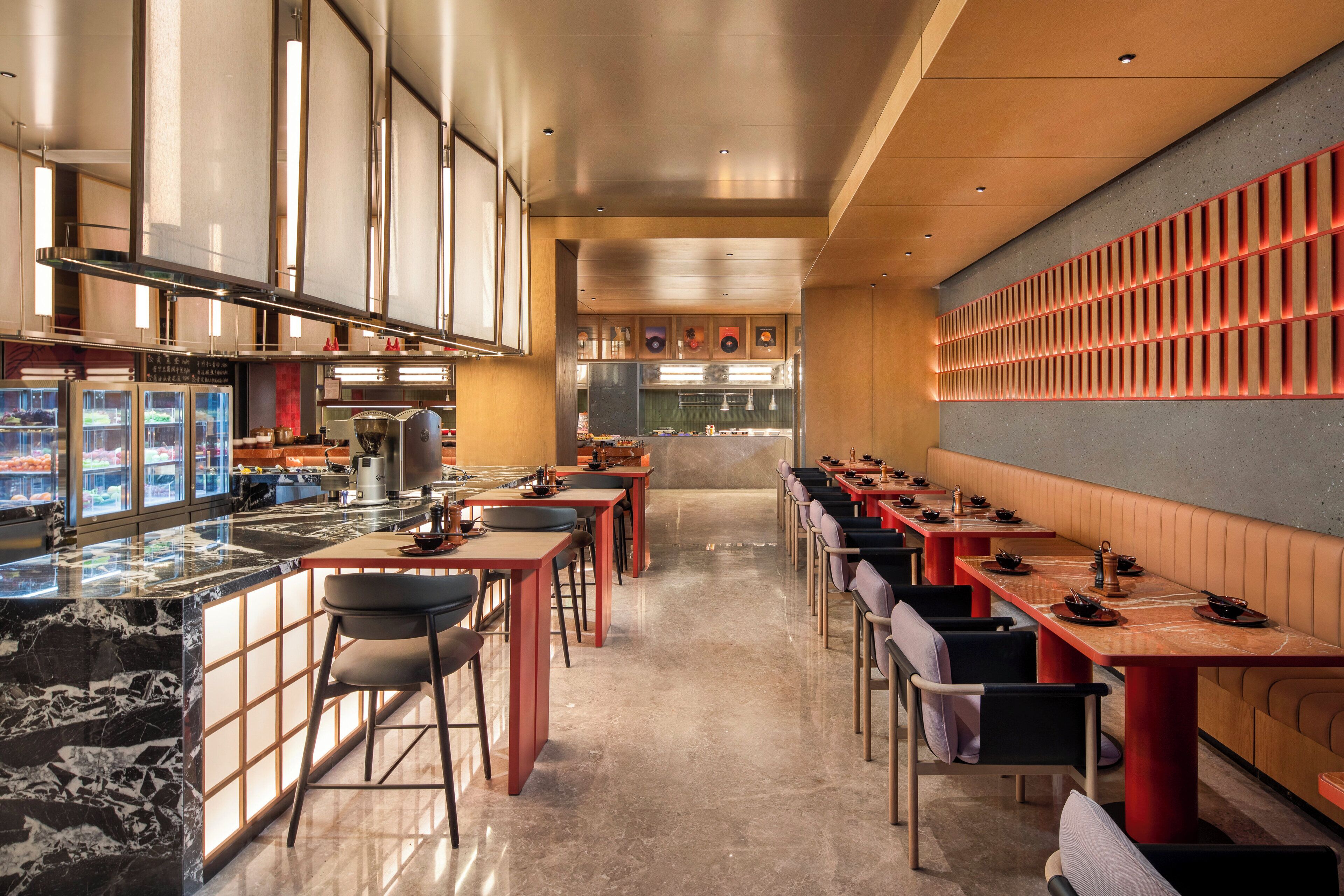 Un restaurante moderno con una barra larga, varias mesas y una zona de bar.