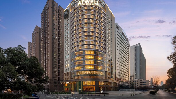 Un hotel moderno con fachada curva, varios pisos y un llamativo letrero ATWELL.