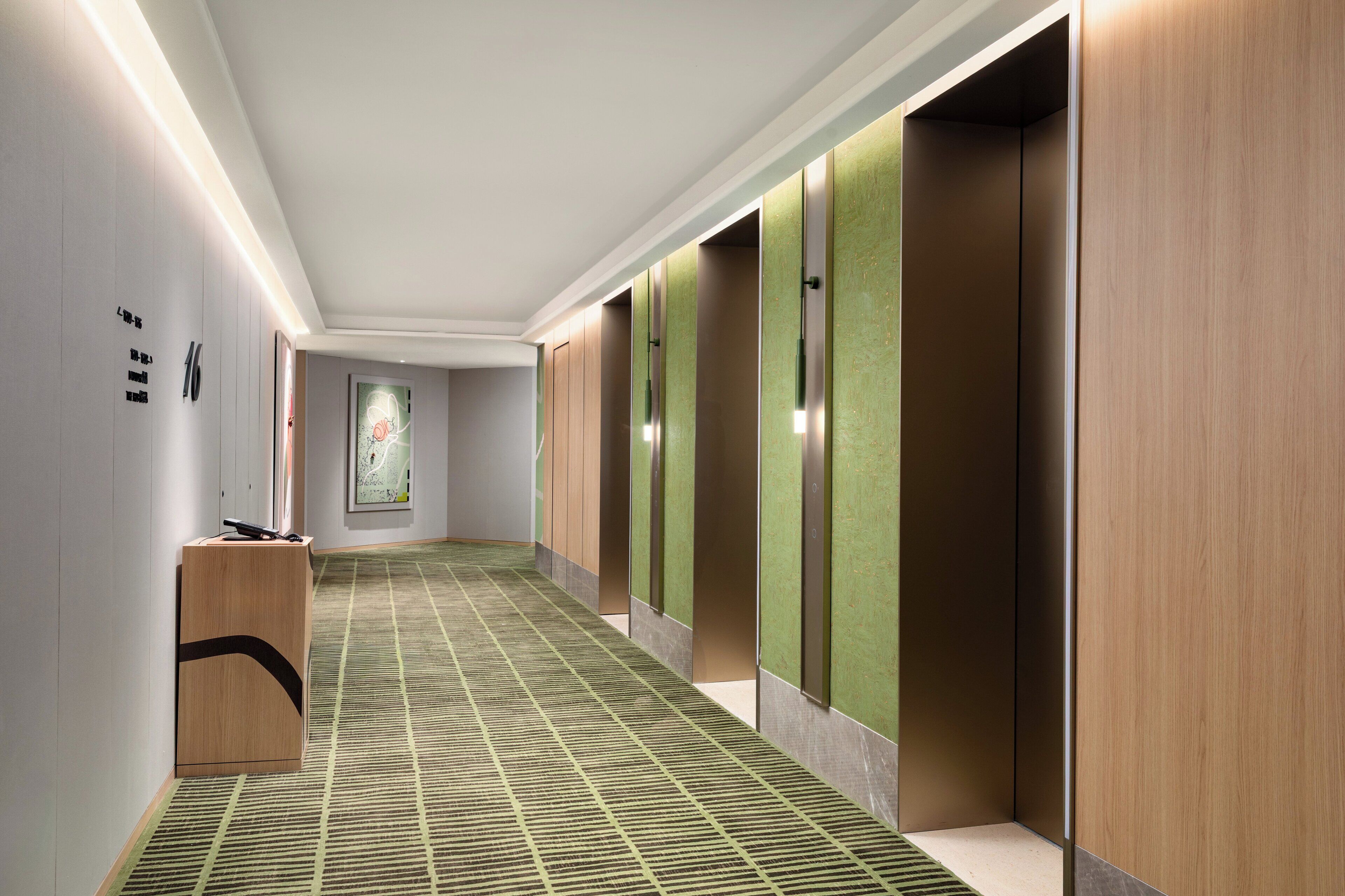 A hallway with a patterned carpet, wooden lockers, and a reception desk.