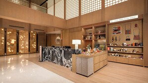A spacious lobby with a marble reception desk, wooden shelving with retail items, and a high ceiling with grid-like windows. - Atwell Suites Hefei City Center By IHG (Hefei)